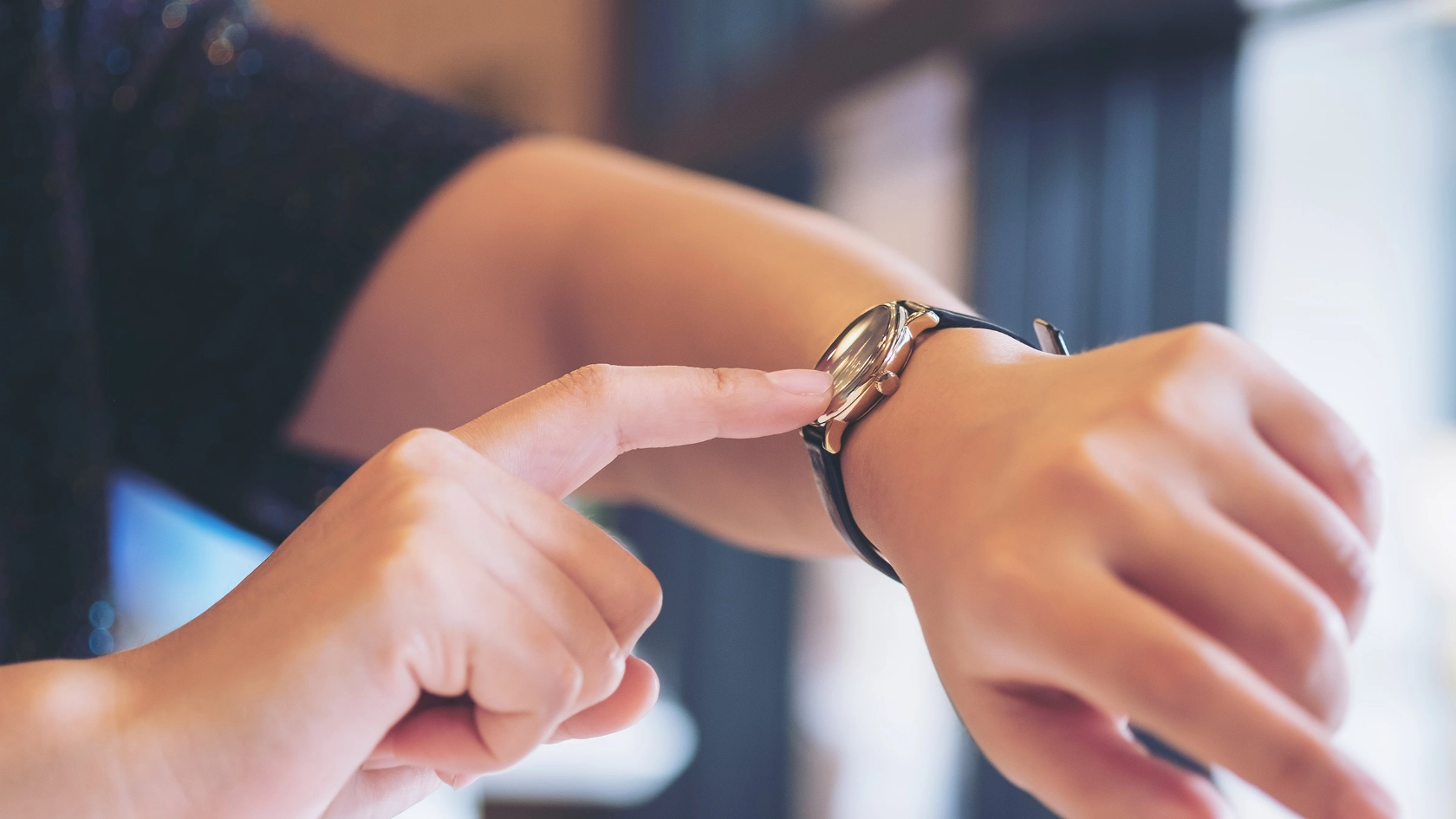 Eine Frau zeigt auf ihre Armbanduhr